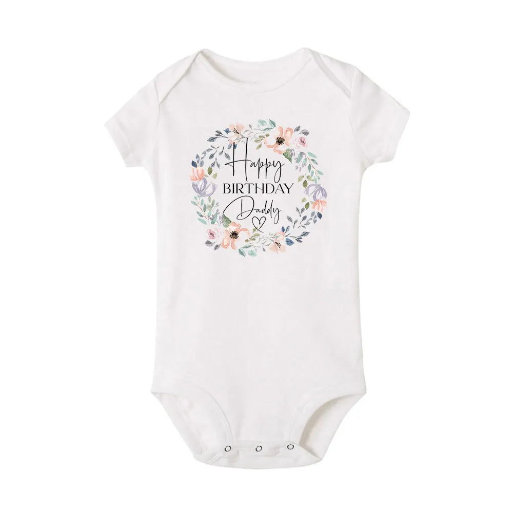 Baby boy wearing a short sleeve "Happy Birthday Daddy" Nova Mart baby bodysuit, summer romper with cheerful birthday theme.