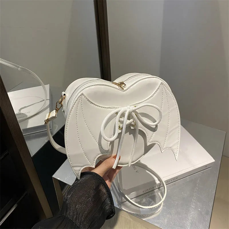 Heart-shaped bag with bat wing design, one-shoulder crossbody style by Nova Mart featuring a unique strap and stylish details.
