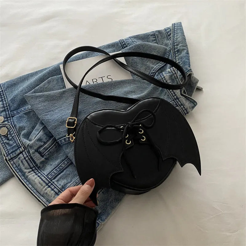 Heart-shaped bag with bat wings design, one-shoulder crossbody style by Nova Mart, featuring a stylish and unique accessory.