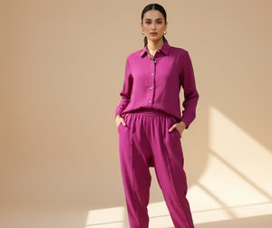 Woman wearing a pink outfit standing in a softly lit room.